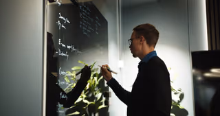 A Distancify specialist developing ideas on a glass whiteboard.